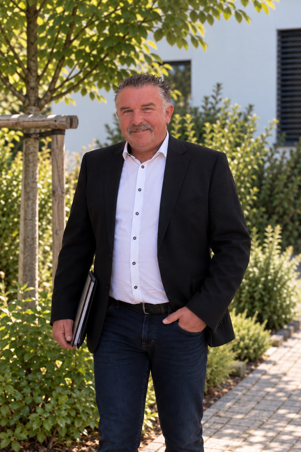 Thorsten Massow mit Mappe vor einem Bürogebäude